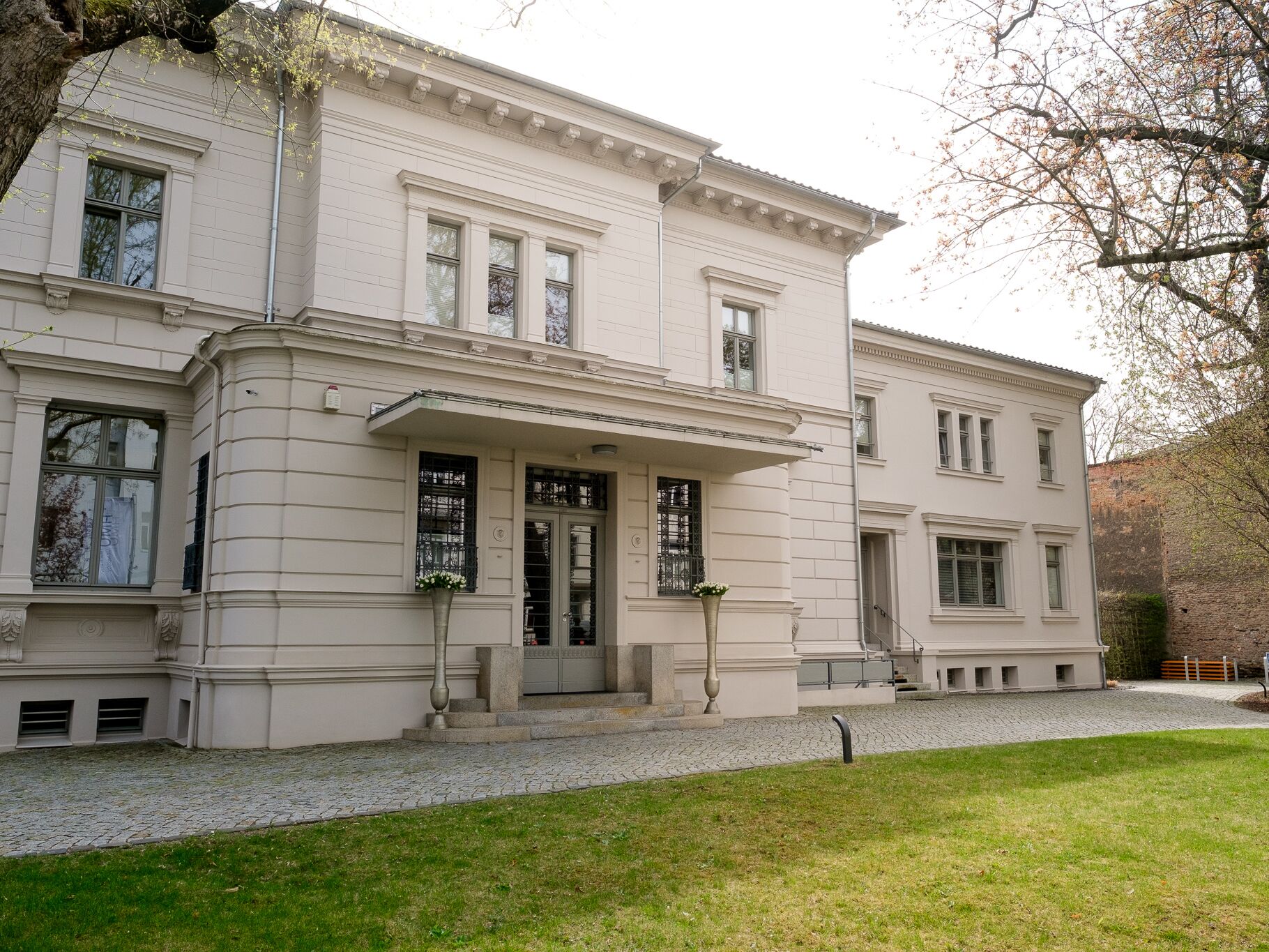 Helles, zweistöckiges Gebäude im klassischen Stil mit gepflegtem Eingangsbereich und Vorgarten.