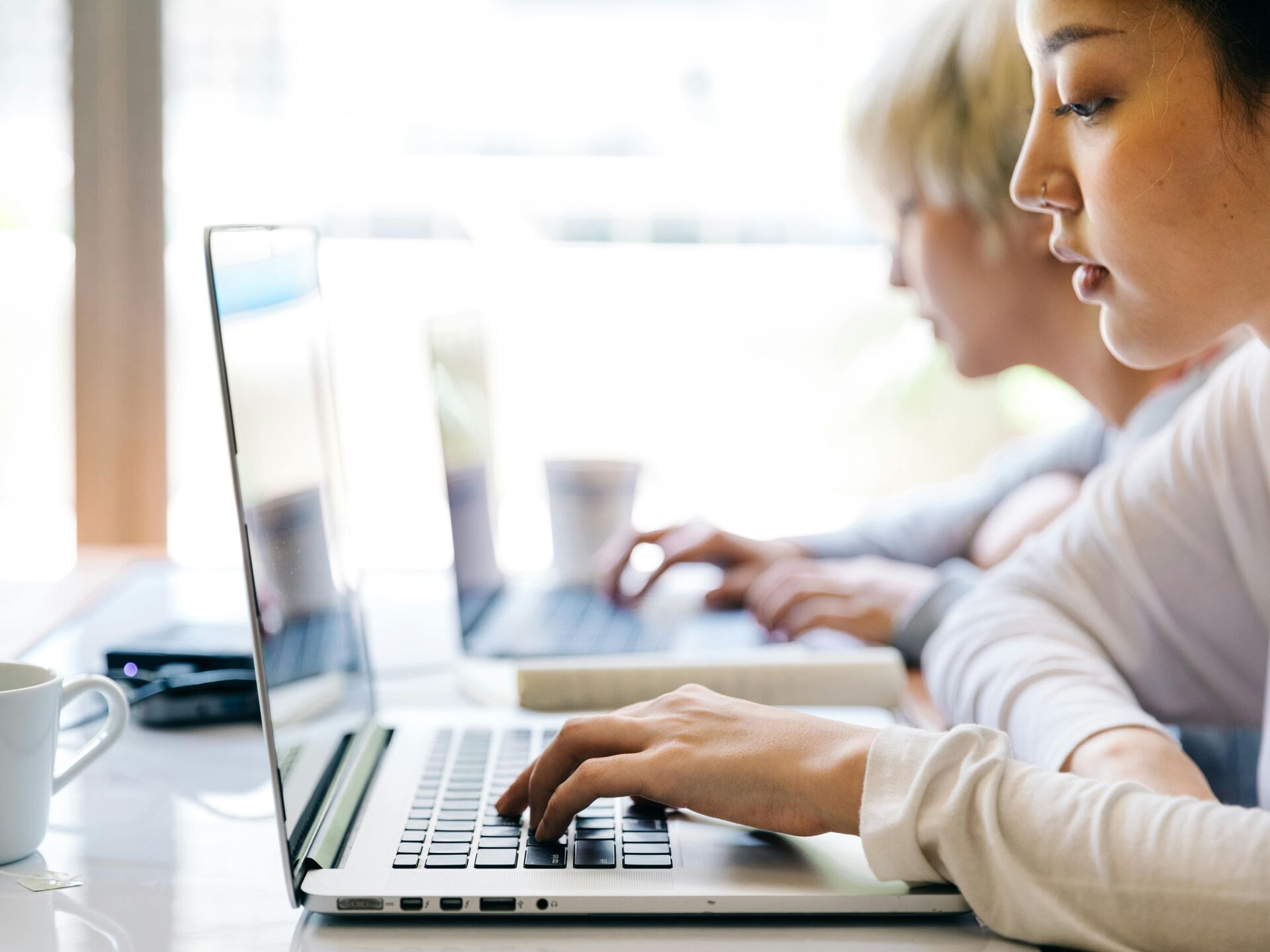 Personen arbeiten konzentriert an Laptops in heller, moderner Umgebung.