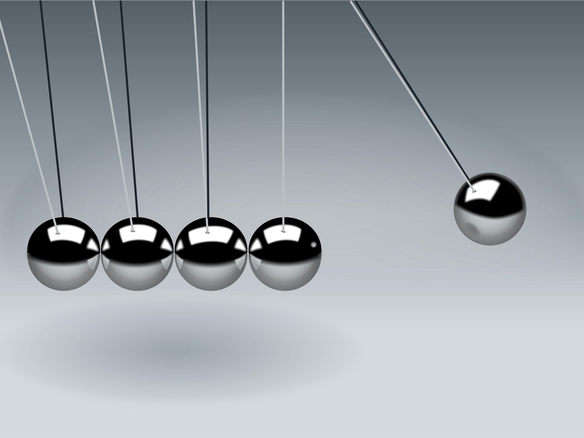 Nahaufnahme eines Newton-Pendels mit schwingenden silbernen Kugeln auf grauem Hintergrund.