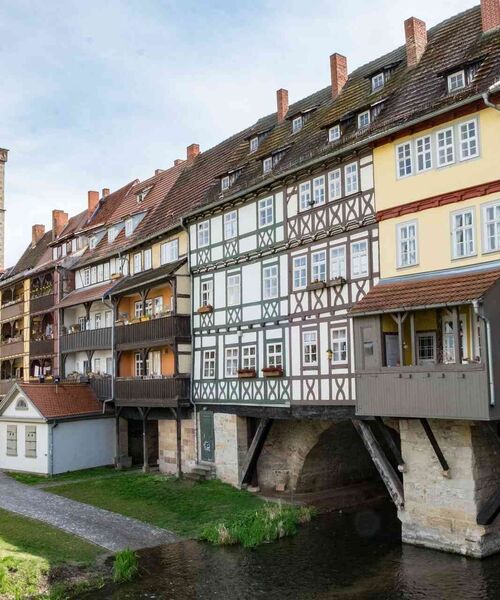 Reihe historischer Fachwerkhäuser über einem kleinen Fluss – Symbol für Tradition und städtisches Kulturerbe.