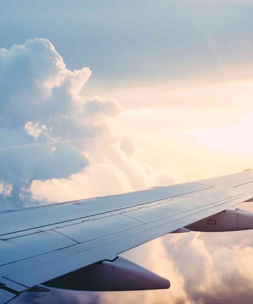 Flugzeugflügel über den Wolken bei warmem Sonnenlicht.