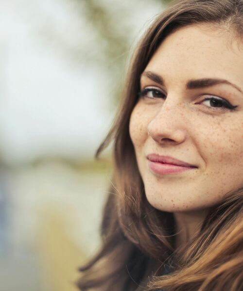 Porträt einer lächelnden jungen Frau im Freien – Ausdruck von Offenheit und Zuversicht.